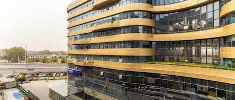 Un immeuble à plusieurs étages doté d’une façade incurvée, de grandes fenêtres et d’un espace commercial situé au rez-de-chaussée.