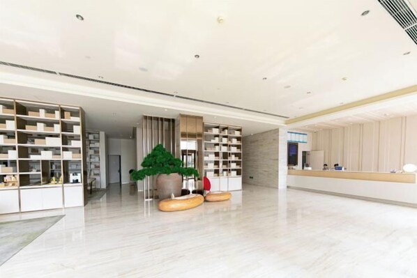A modern hotel lobby with a spacious layout, a reception desk, and a large potted plant. - JI Hotel (Zhengzhou Xinzheng International Airport) (Xinzheng)