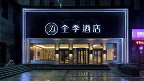 Een hotelentree met een modern ontwerp, met een opvallend verlicht bord en een draaideur.