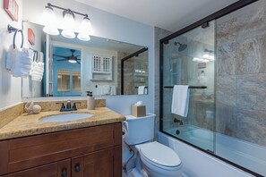 Baño con lavamanos, inodoro y cabina de ducha de vidrio.
