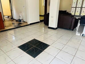 A hotel lobby with a checkered floor pattern, a reception desk, and a large window with decorative iron bars.