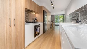 Une cuisine moderne avec des meubles en bois, des appareils électroménagers en acier inoxydable et un dosseret en marbre.