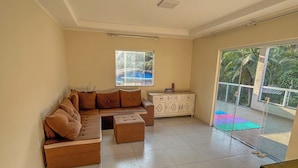 Un espacio habitable amplio con un sofá modular, un reposapiés y un mueble bajo. Una ventana grande ofrece vistas al exterior.