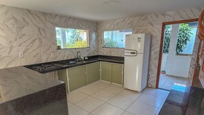 Una cocina con paredes de mármol, encimera negra y refrigerador blanco.
