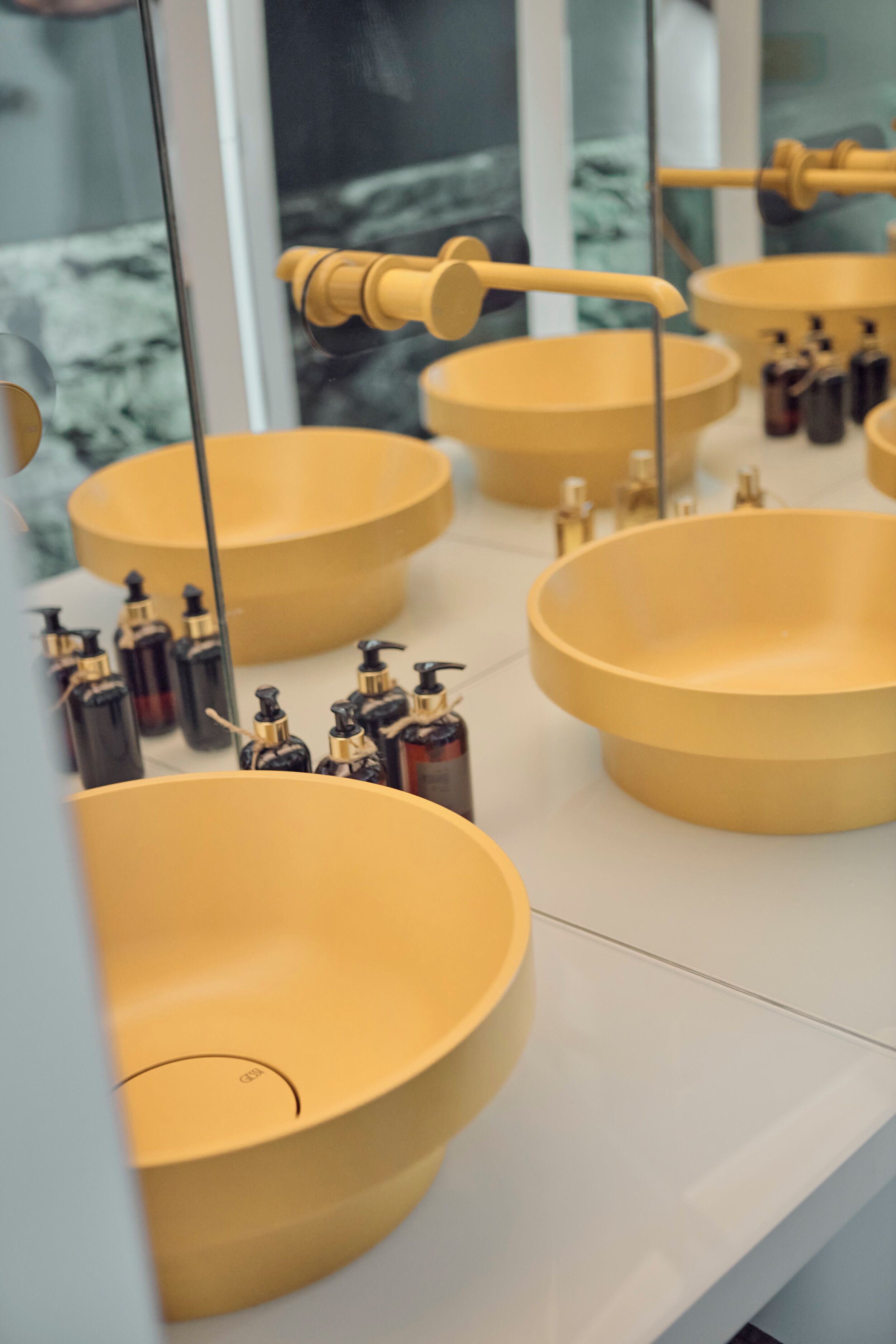 A bathroom with multiple yellow sinks and toiletries.
