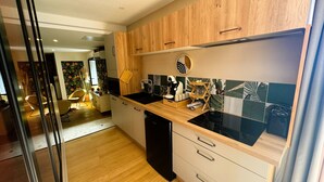 A modern kitchen with wooden cabinets, a black countertop, and a tiled backsplash. - Le diX - Classic Room - Vallabrix (Vallabrix)