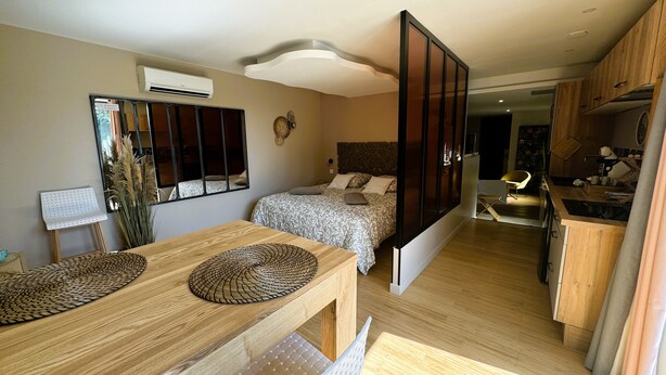 A modern apartment with a dining area, a bedroom with a large bed, a kitchen, and a living area with a sofa. - Le diX - Classic Room - Vallabrix (Vallabrix)