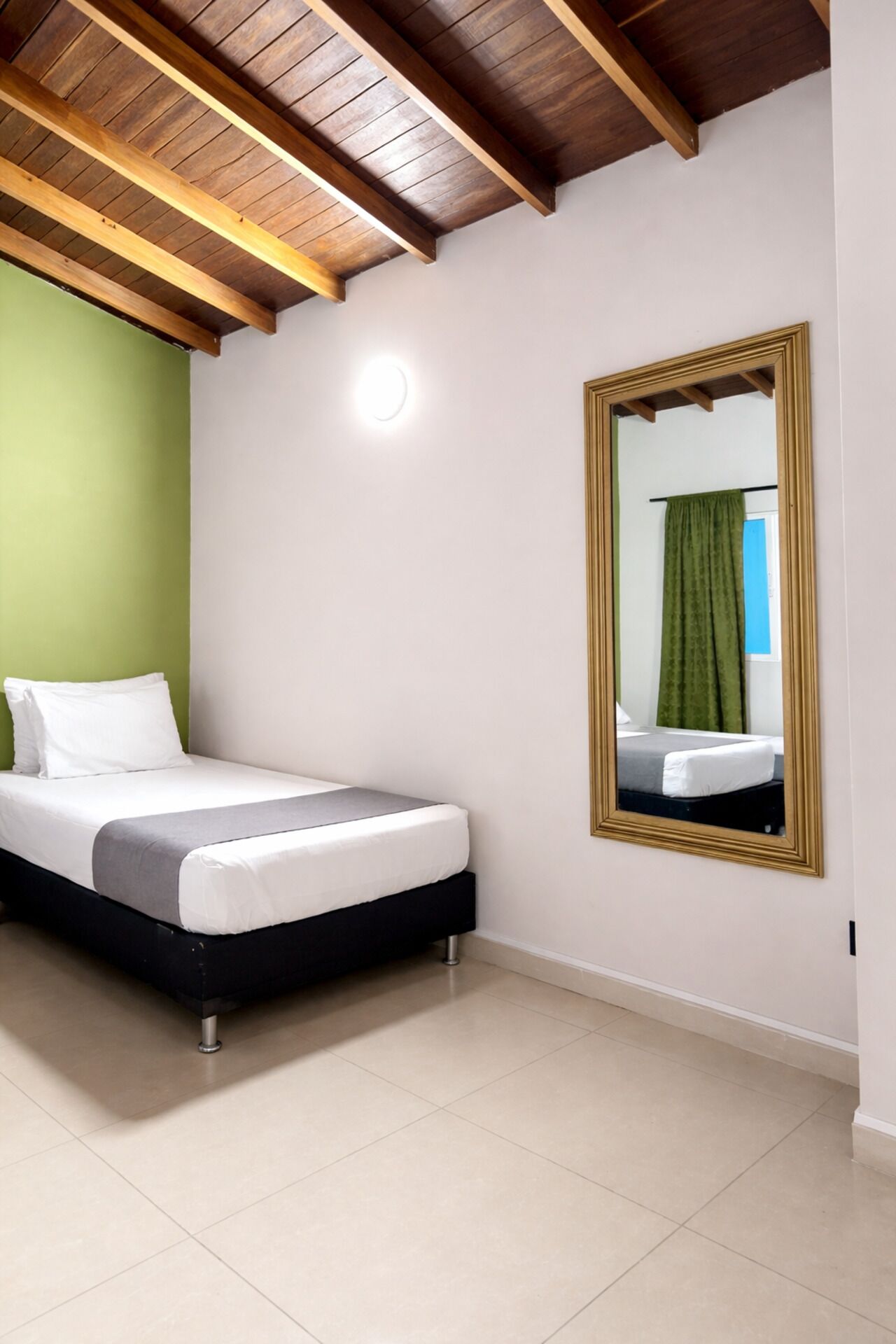 A bedroom with a bed, a mirror, and a green wall.