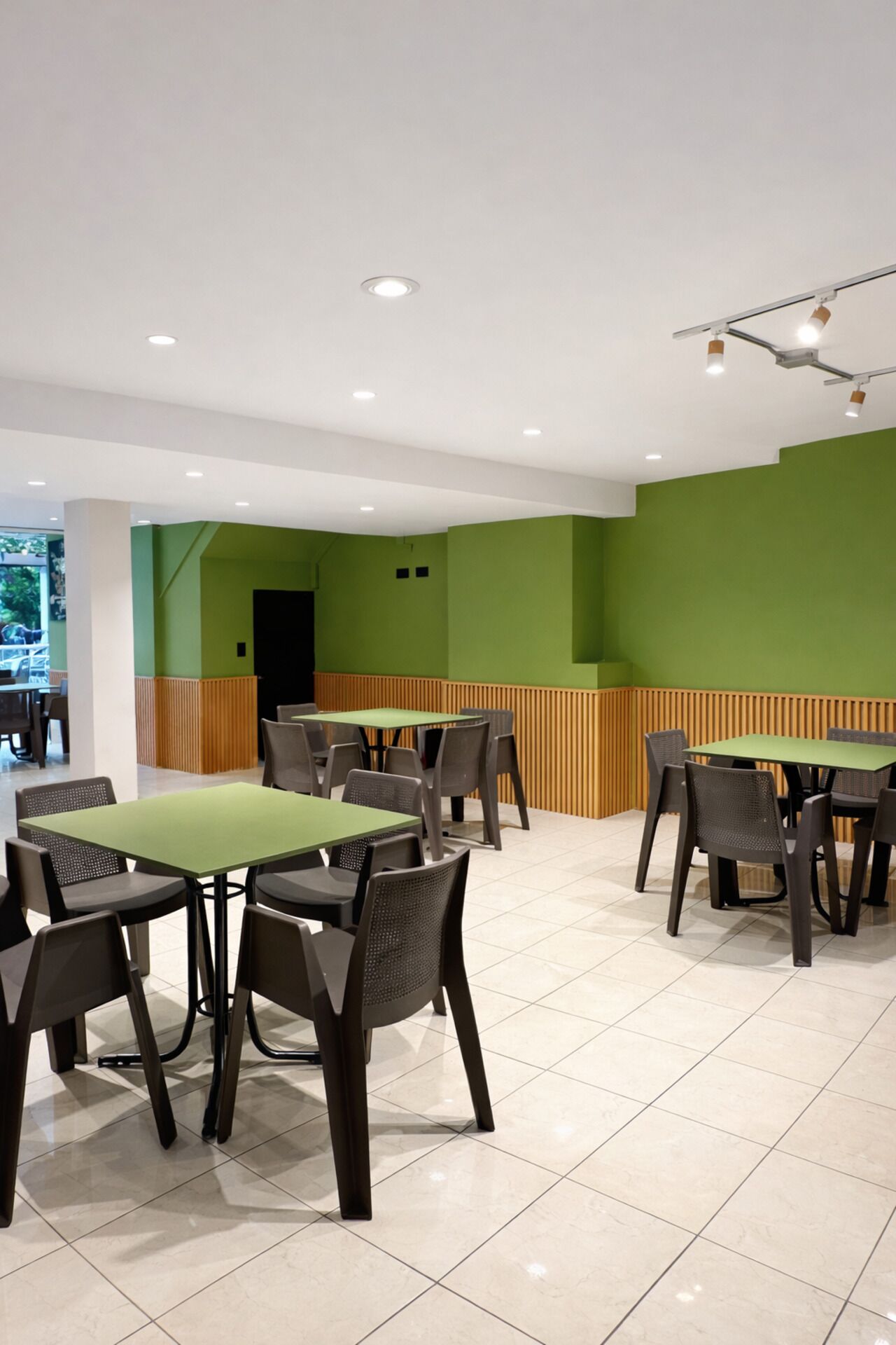 Un comedor moderno con paredes verdes, varias mesas y sillas.