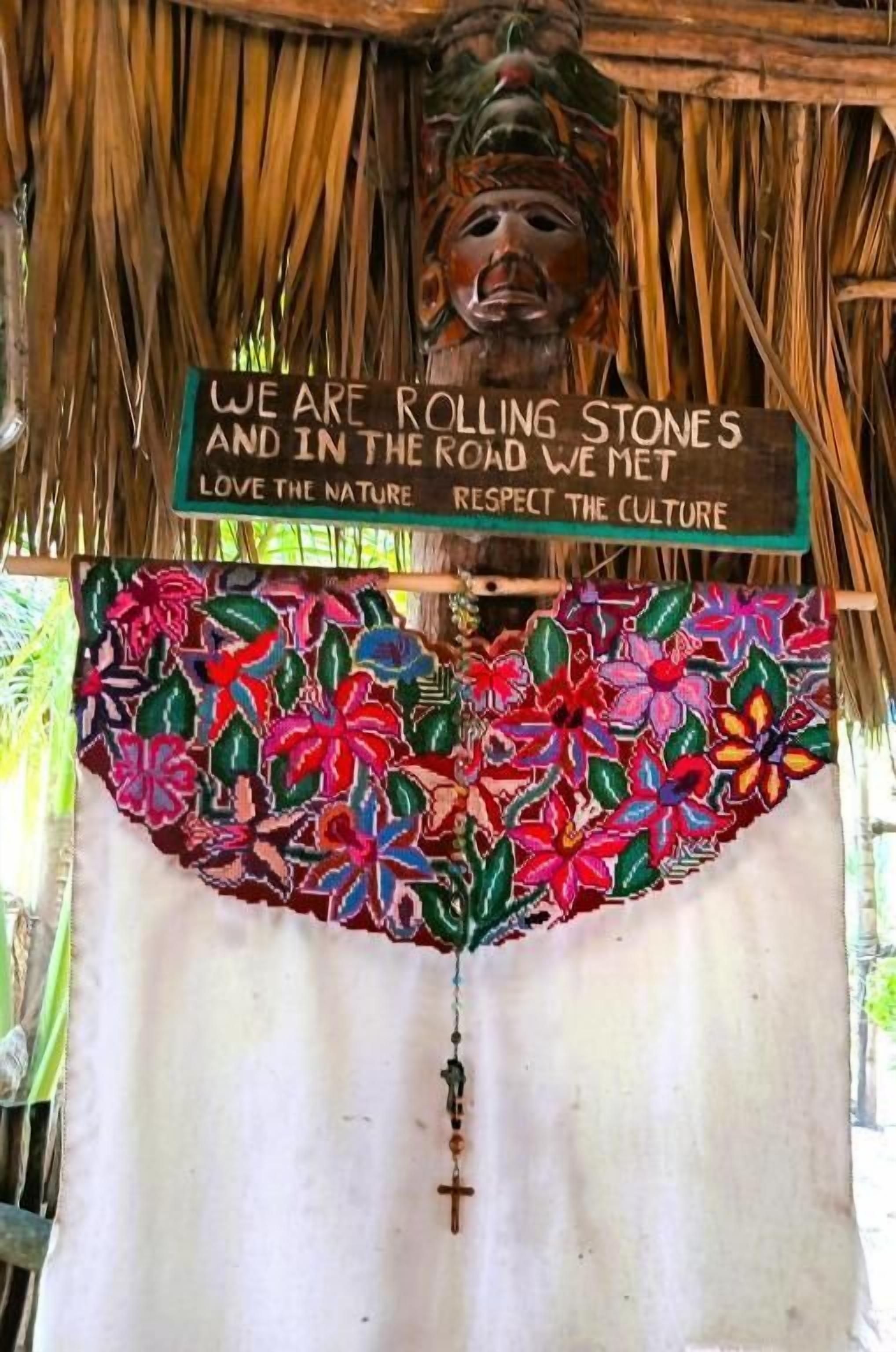A thatched structure with a sign stating "We are rolling stones and in the road we met love the nature respect the culture."