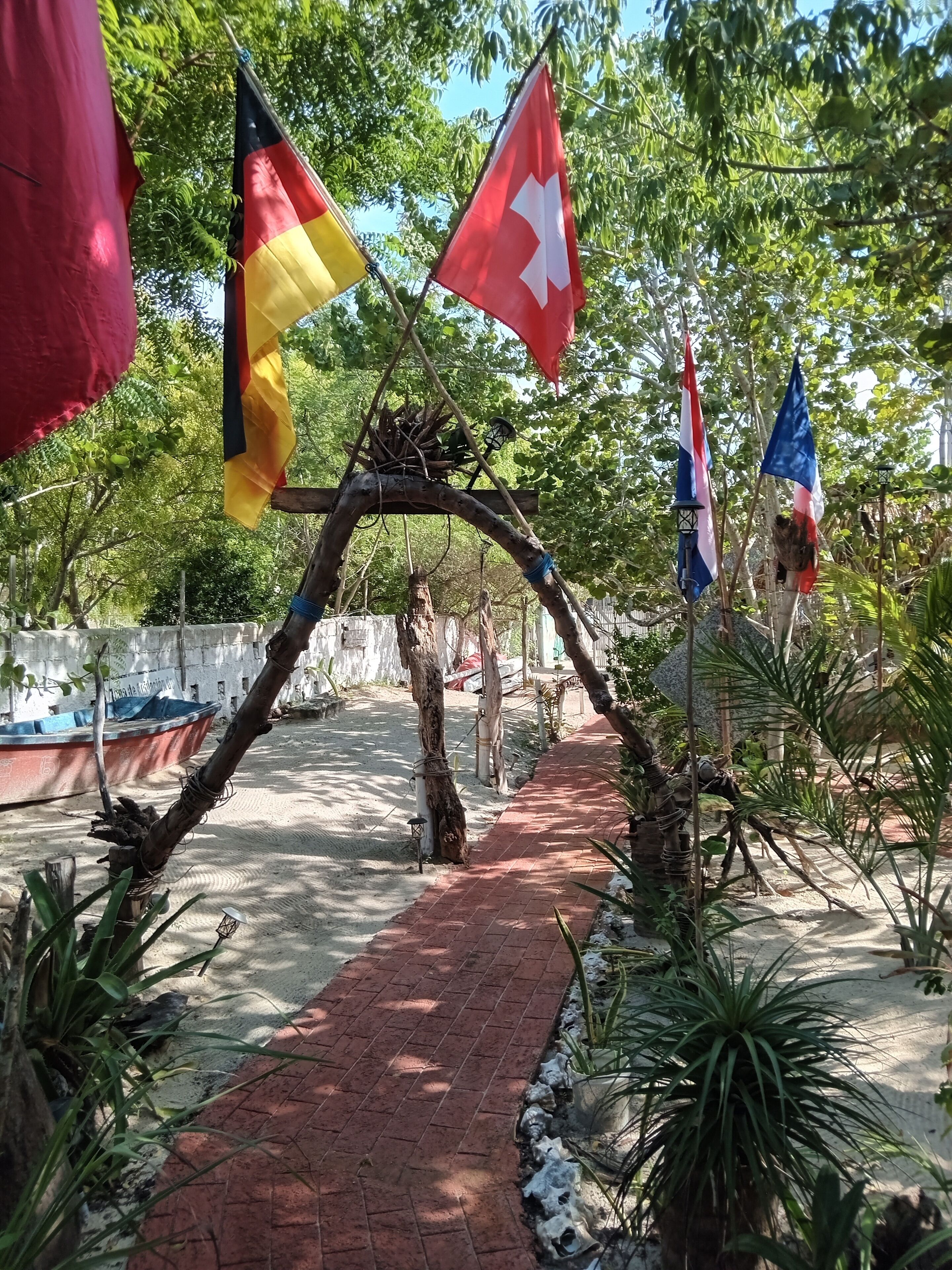 A pathway with flags, a boat, and a tree arching over the path.