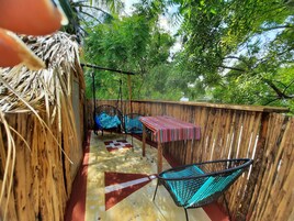 A wooden deck with a table and two chairs, surrounded by lush greenery.