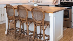 A kitchen with white cabinets, a wooden island with bar stools, and pendant lighting. - Historic Downtown St Marys Loft Experience (Saint Marys)
