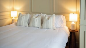 A neatly made bed with white linens and striped pillows, flanked by two bedside lamps on wooden nightstands. - Historic Downtown St Marys Loft Experience (Saint Marys)