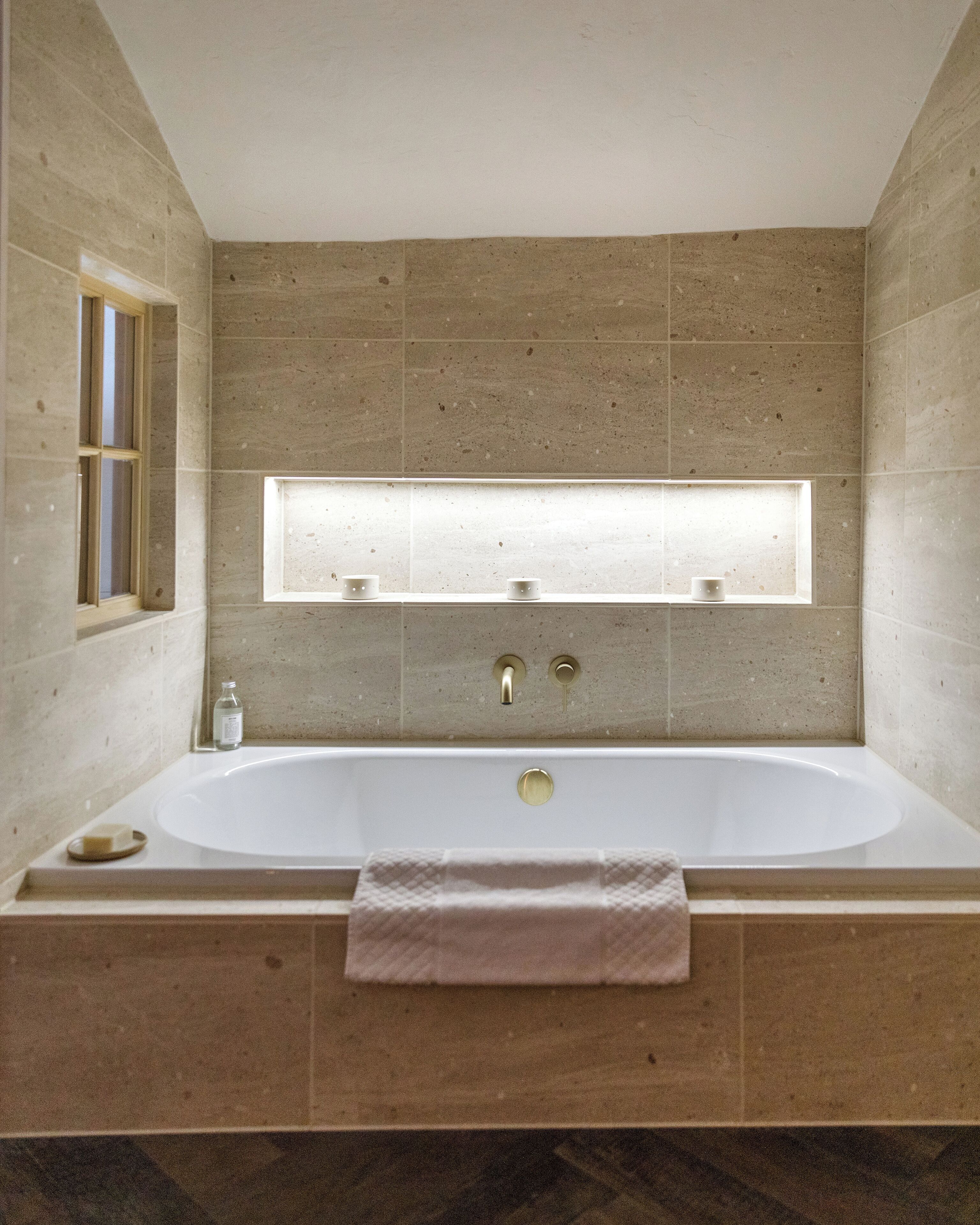 Un baño moderno con una bañera independiente, un ventanal sobre el lavabo y una toalla colgada de la bañera.