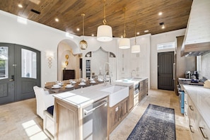 A spacious kitchen with a central island, wooden ceiling, and pendant lighting.