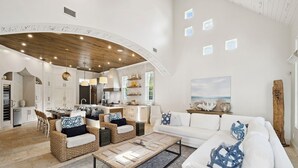 A spacious living area with a kitchen, white furniture, and a wooden ceiling. - Dreamy retreat—5-min to beach, private pool, LSV, & home theater | Sleeps 20! (Seagrove Beach)