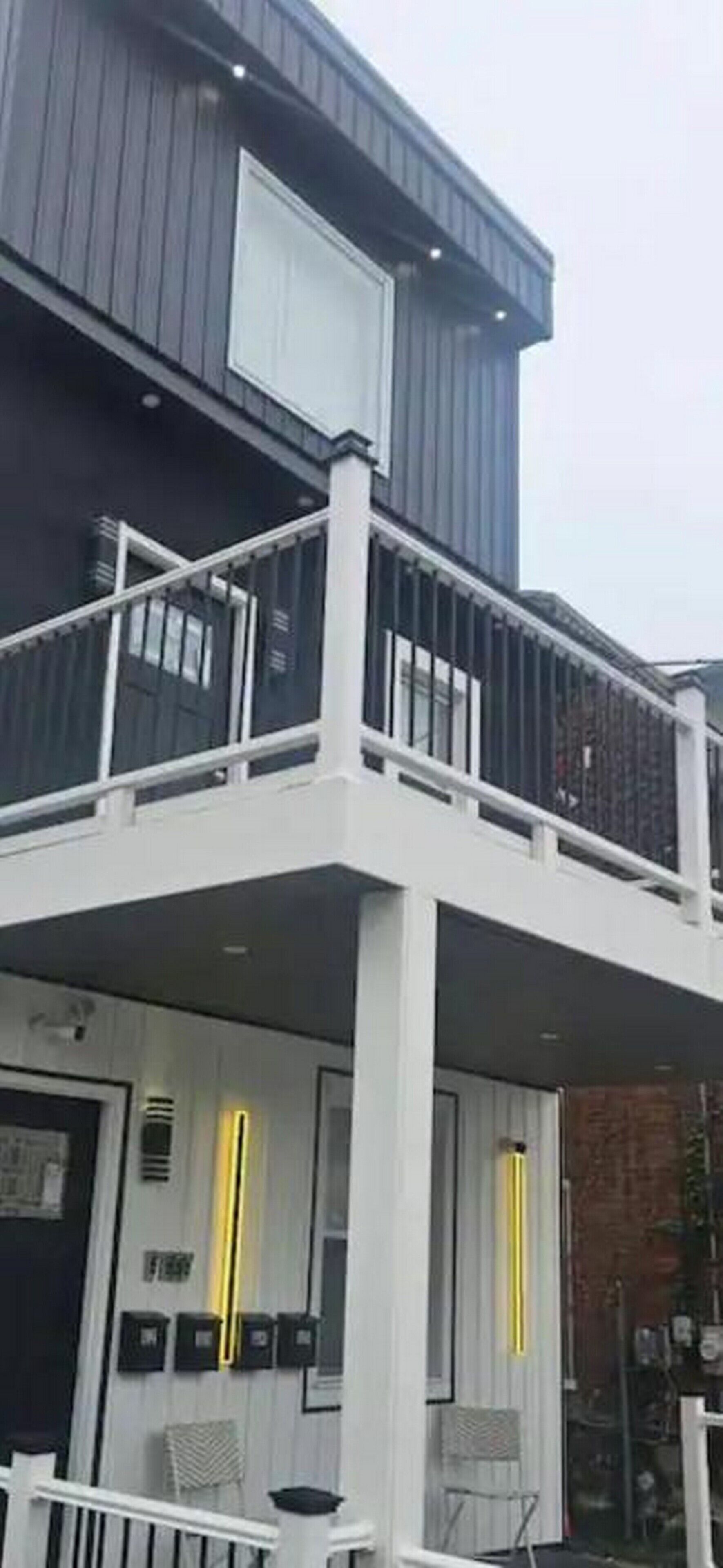 A modern two-story building with a balcony, large windows, and a visible door.