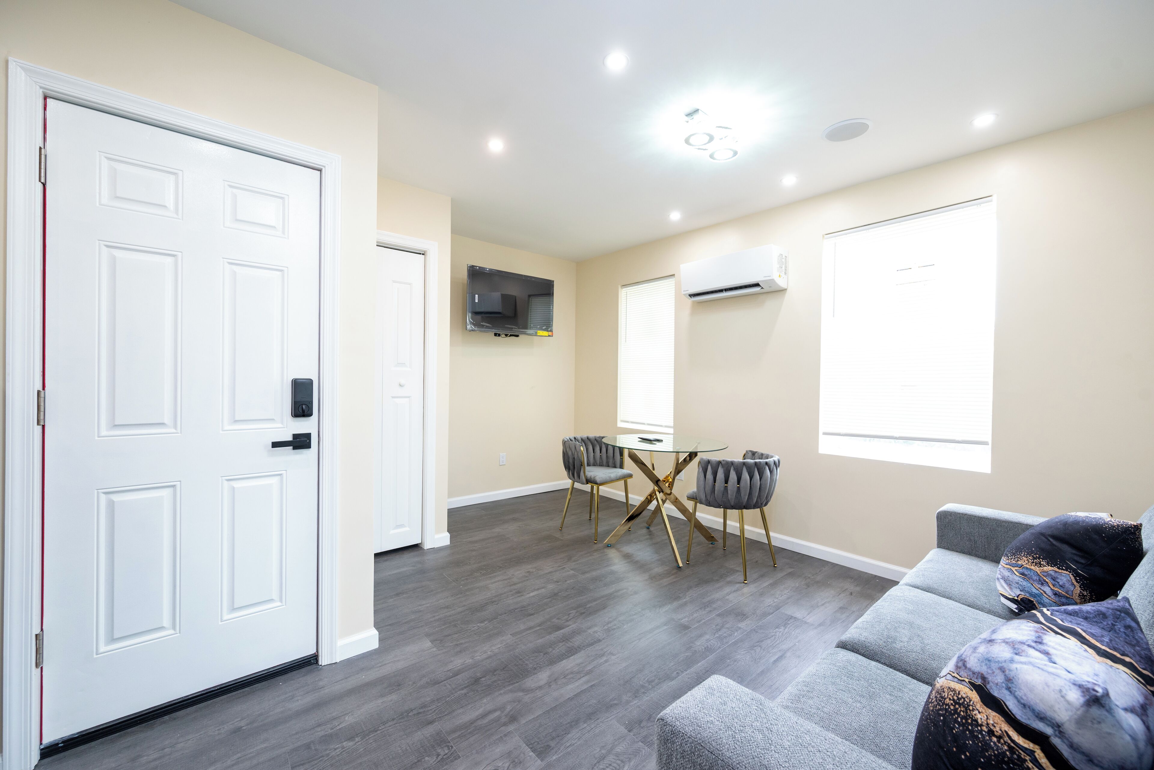 A modern living room with a grey sofa, a small table, and a TV mounted on the wall.