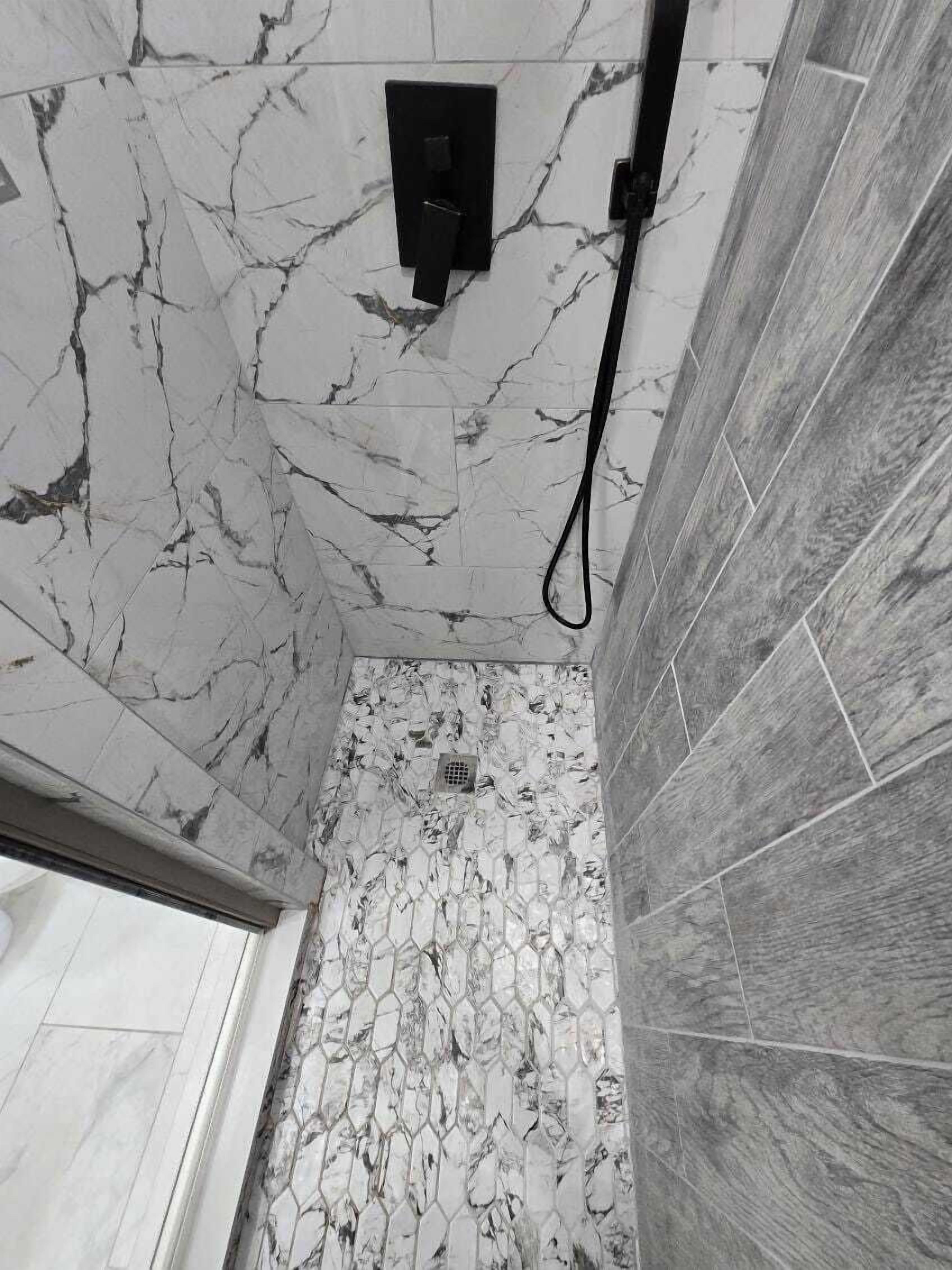 Un baño con paredes de mármol y zona de ducha.