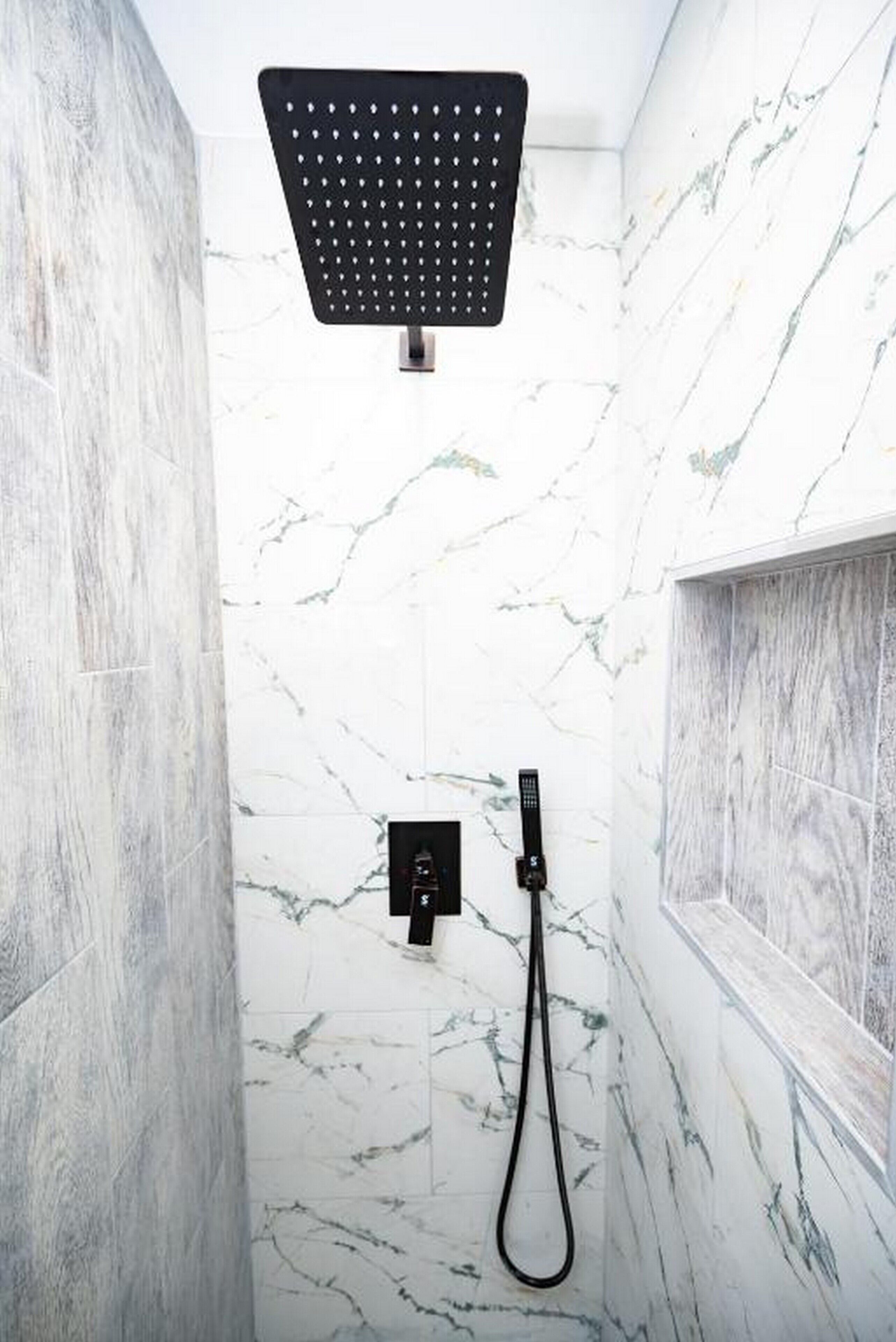 Eine moderne Dusche mit Duschkopf, Handbrause und Bedienfeld an der Wand.