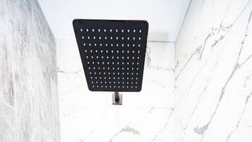 Eine moderne Dusche mit Duschkopf, Handbrause und Bedienfeld an der Wand.