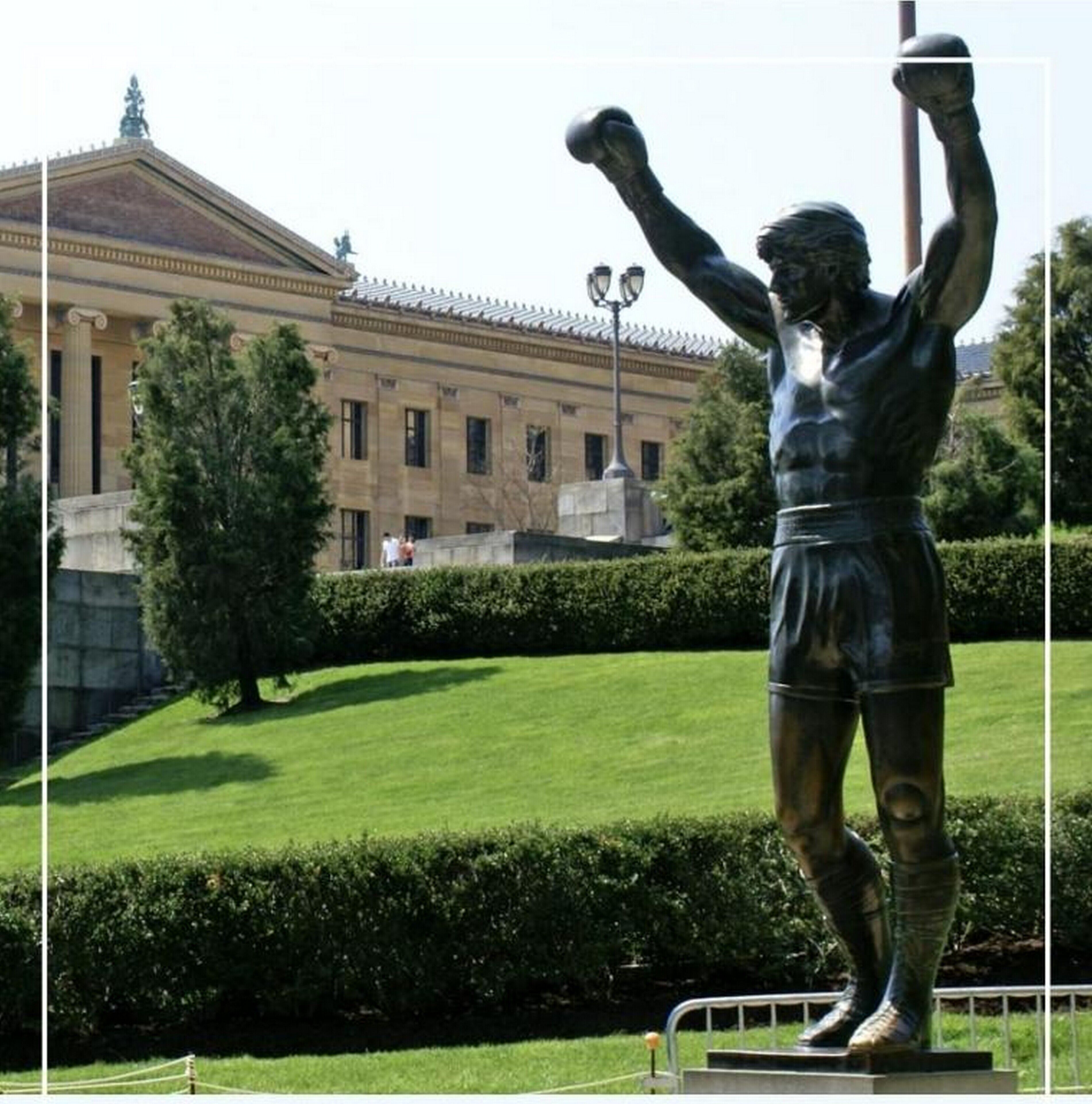 A statue of a boxer in a public square with a building in the background.