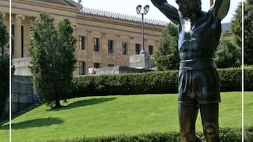 A statue of a boxer in a public square with a building in the background.