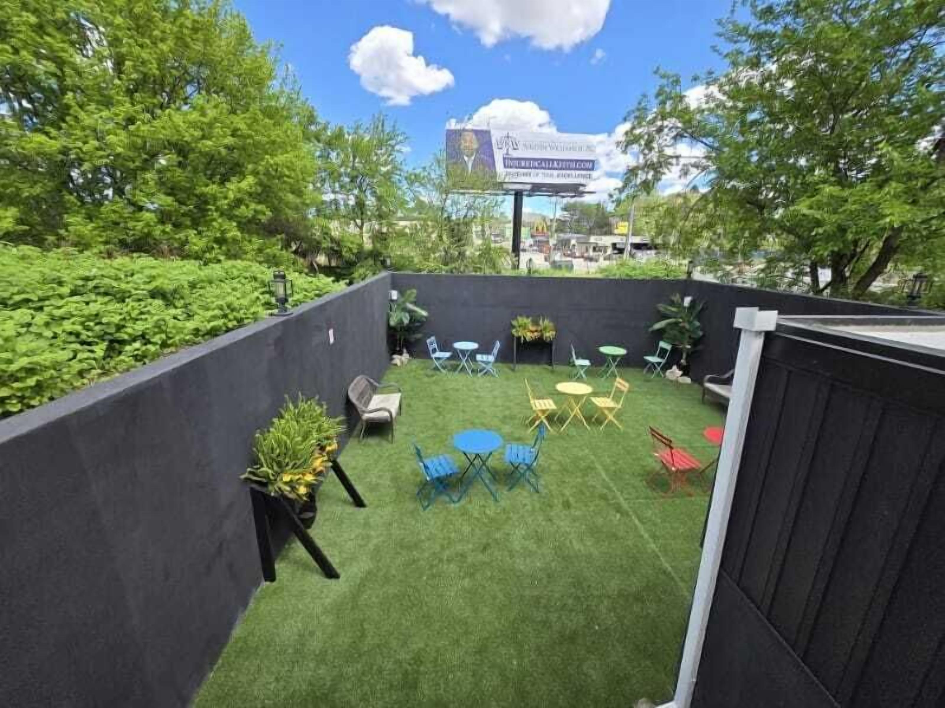 A rooftop patio with artificial grass, outdoor furniture, and a view of the city skyline.