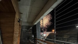 Un couloir doté d’un plancher en bois, d’une rambarde en métal et d’un plafond en béton.