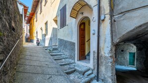 Una calle estrecha con escalones de piedra que conducen a un edificio con una puerta de madera y un cartel con el número 21.