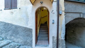 Una escalera estrecha que conduce a un edificio con una puerta de madera y un pequeño ventanal.