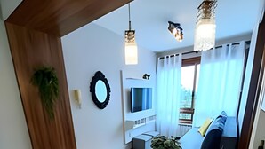 Moderni ruokailutila, jossa on puinen pöytä, keltaiset tuolit, televisio ja näkymä parvekkeelle, jossa on sohva.