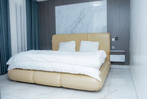 Relax in a spacious room with a large bed, beige headboard, and white bedding.