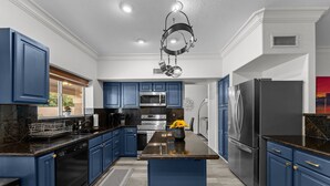 A modern kitchen with blue cabinets, stainless steel appliances, and a central island. - Ultimate Luxury: Home with a Pool and Private Gym! (Tempe)