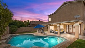 A backyard with a swimming pool, patio furniture, and a house with a satellite dish. - Ultimate Luxury: Home with a Pool and Private Gym! (Tempe)