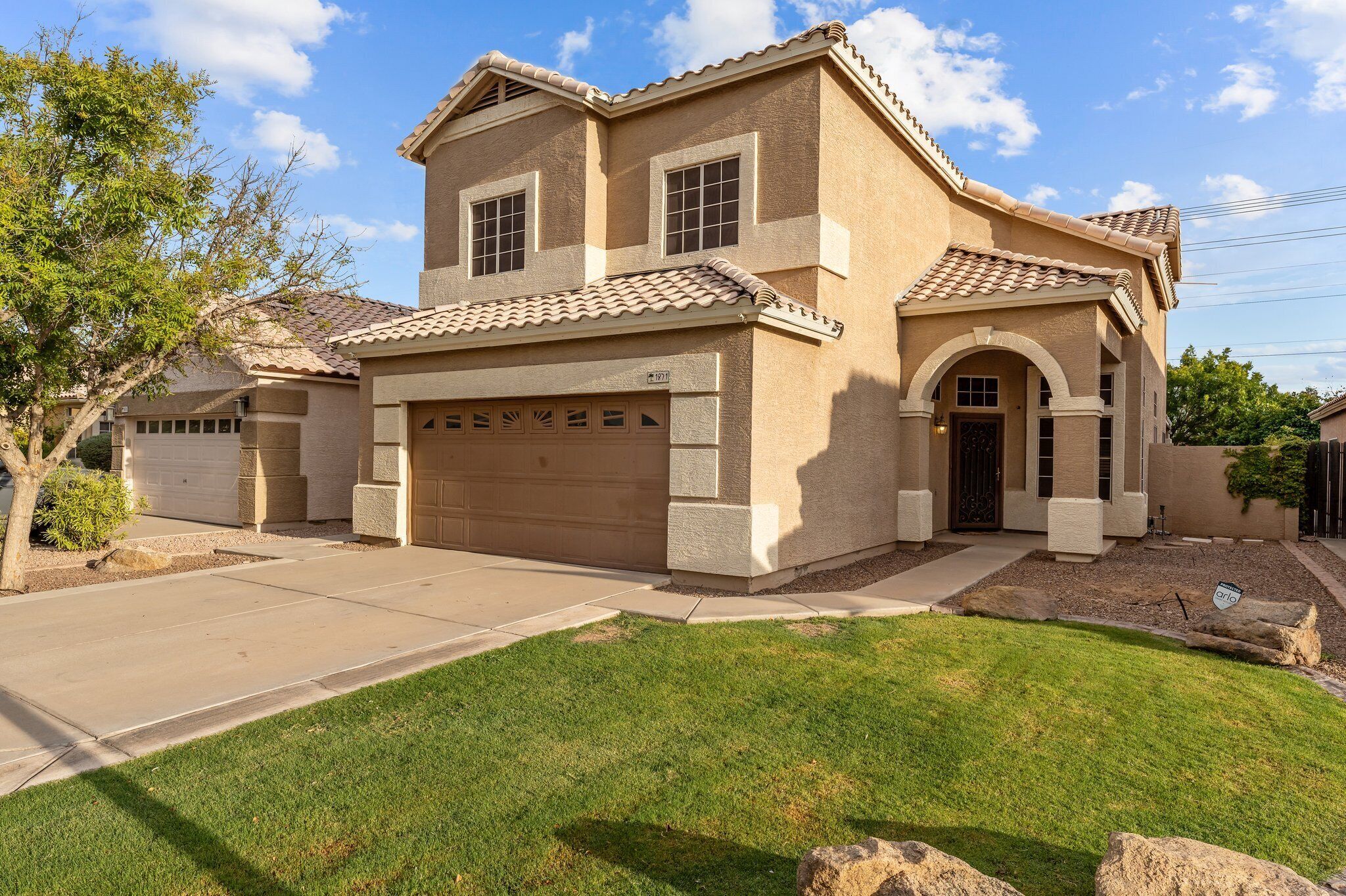 A two-story house with a garage, a well-maintained lawn, and a clear sky.