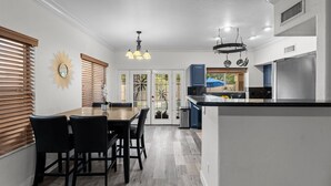 A modern kitchen with a central island, white cabinetry, and a dining area with a wooden table and chairs. - Ultimate Luxury: Home with a Pool and Private Gym! (Tempe)