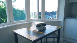 A small table with a stack of books in a room with large windows.