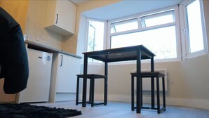 A compact kitchen with a window, a small table, and a refrigerator.