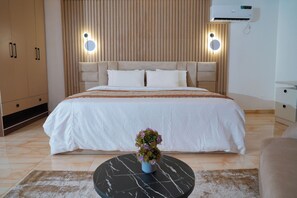 Ein Schlafzimmer mit einem großen Bett, einem Nachttisch mit Blumenvase und einer Wand-Klimaanlage.