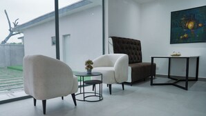 A modern living room with a sofa, armchair, and a small table with a potted plant. - Majestic Courts (Lagos)
