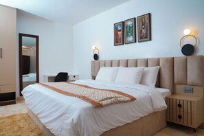 Un dormitorio ordenado con una cama grande, mesitas de noche, un espejo y obras de arte en la pared.