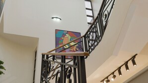 A multi-level interior with a staircase featuring a glass ceiling and metal railings. - Majestic Courts (Lagos)