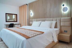 A neatly made bed with a patterned throw, a bedside table with a lamp, and a wall-mounted mirror. - Majestic Courts (Lagos)