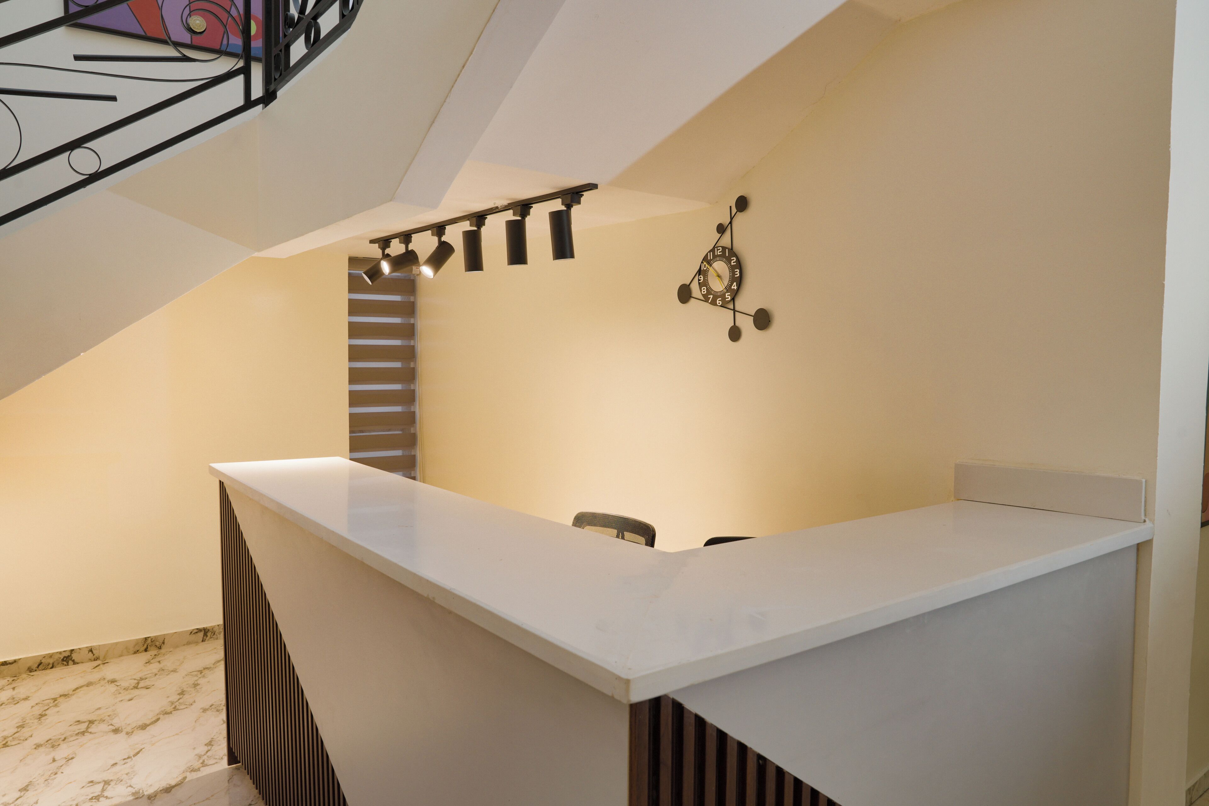 Una cocina moderna con encimera blanca, lámpara colgante y un reloj en la pared.