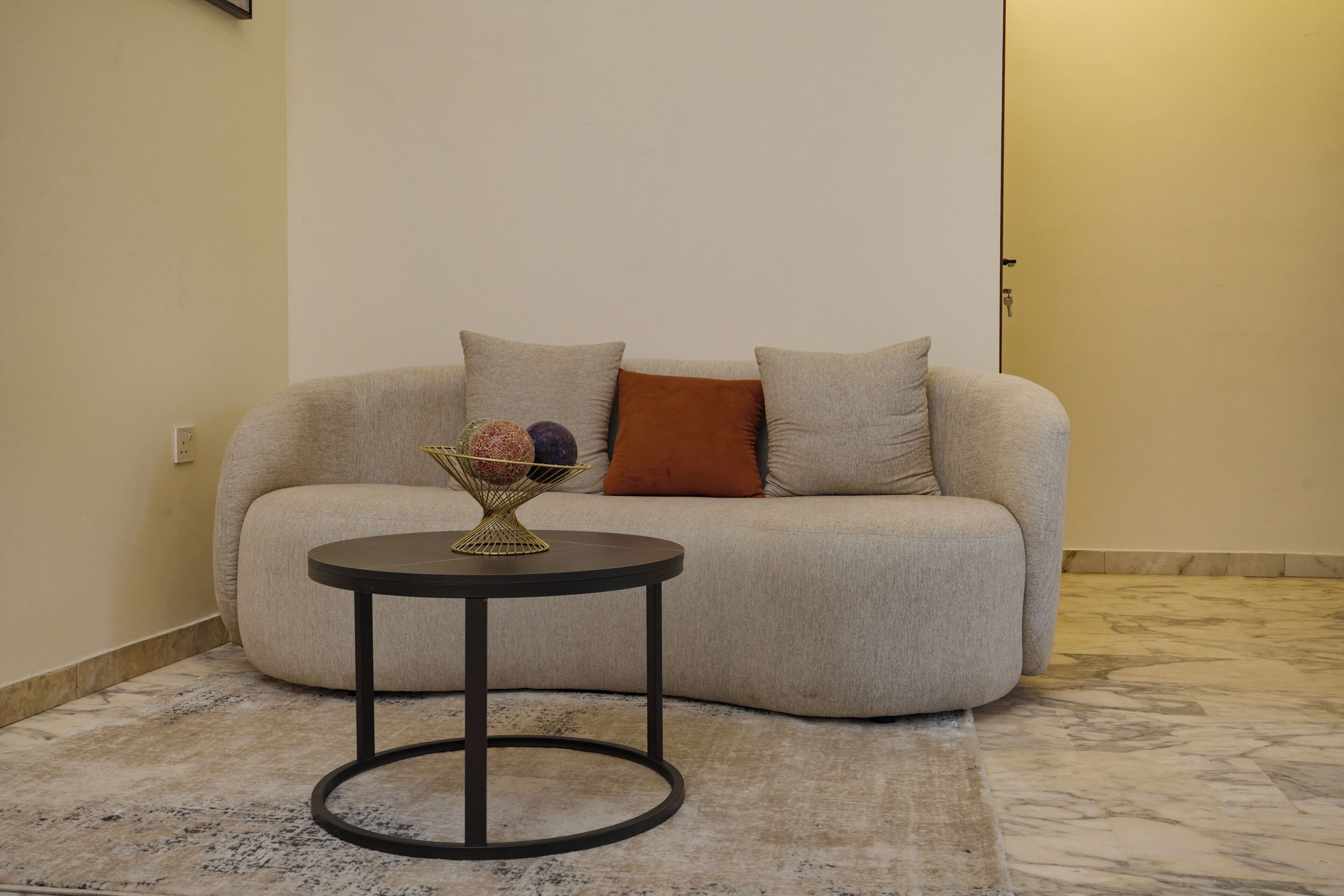 A living room with a sofa, a small round table, and a decorative bowl.