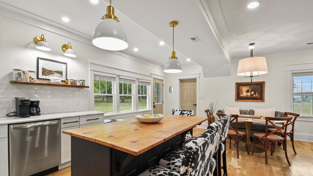 A modern kitchen with a wooden island, stainless steel appliances, and pendant lighting.
