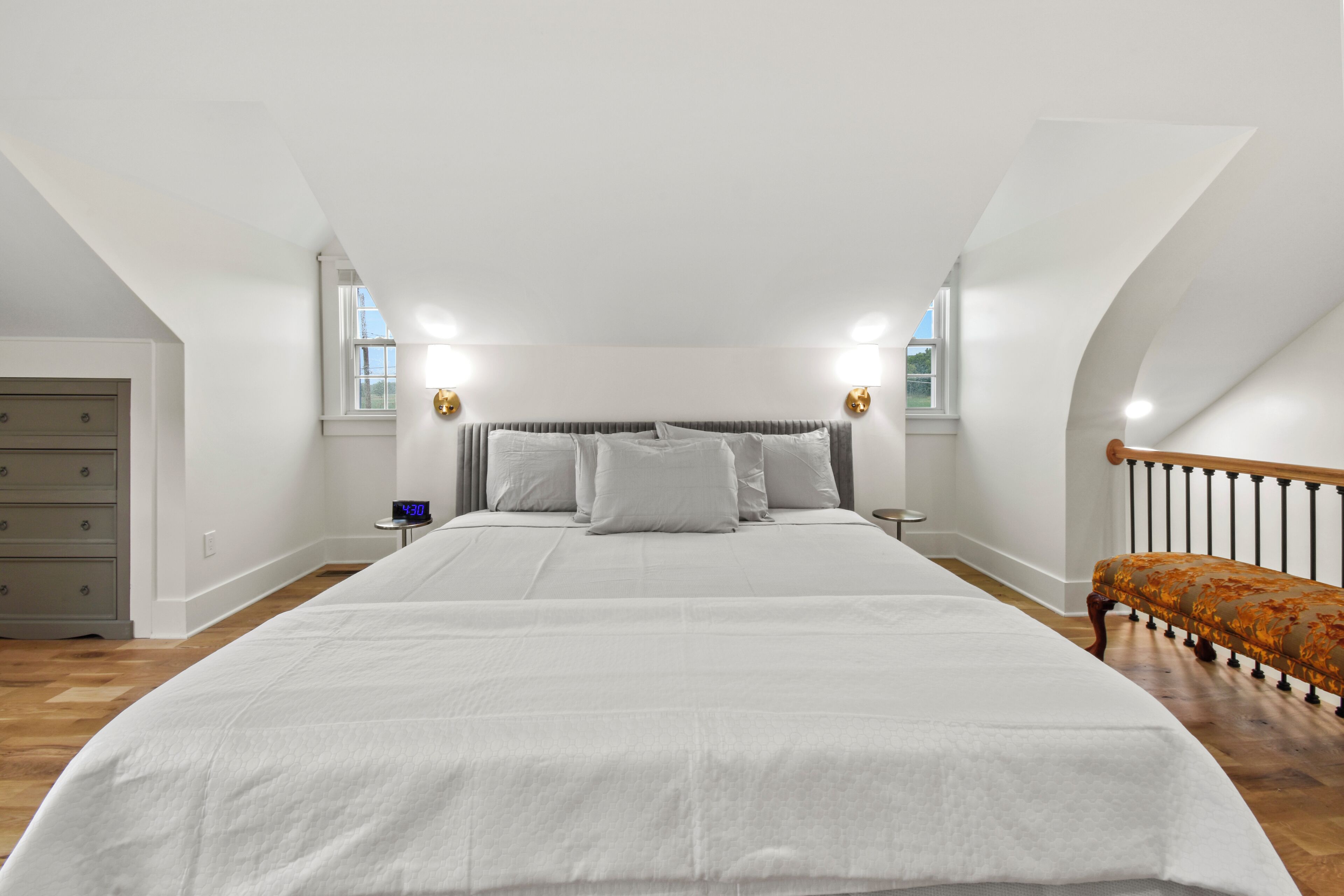 Ein geräumiges Schlafzimmer mit einem großen Bett, einem Nachttisch, einer Kommode und einem Fenster.