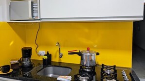 Una cocina con microondas, cafetera, pileta, estufa y una olla sobre la encimera.